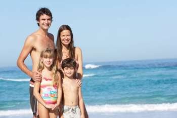 Young Family Standing On Sandy Beach on Holiday