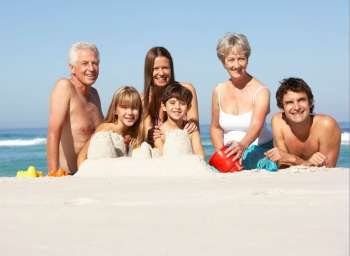 Three Generation Family Building Sandcastles On Beach Holiday