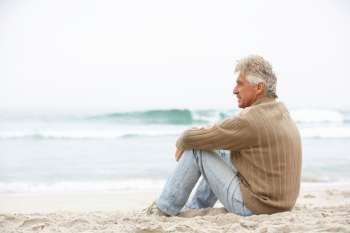 Senior Man On Holiday Sitting On Winter Beach