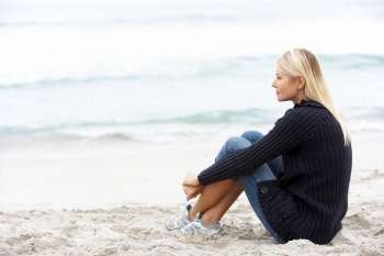 Young Woman On Holiday Sitting On Winter Beach