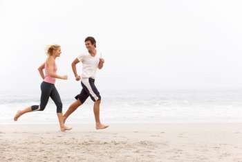 Young Couple Running Along Winter Beach