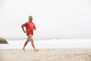 Senior Man On Holiday Running Along Winter Beach