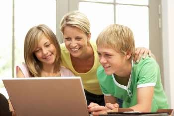 Mother And Teenage Children Using Laptop At Home