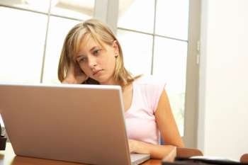 Worried Looking Teenage Girl Using Laptop At Home