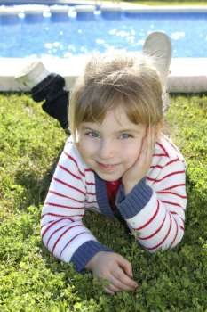 blond little girl laying on pool grass