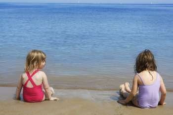 two sisters sit on beach bathing suit swimsuit