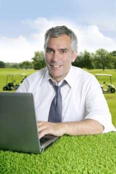 senior businessman golf course working computer green grass desk