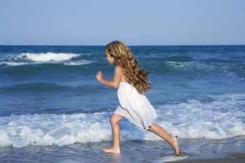 Little girl running beach shore splashing water in blue sea