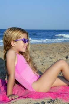 Trendy fashion little summer girl on beach sand tanning with sunglasses