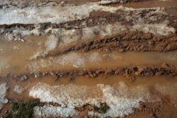 ice on mud red clay soil road with tyres lines