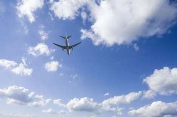 Aeroplane gliding through  a cloudy blue sky
