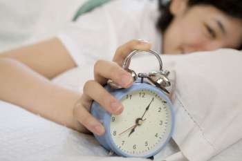 person pushing snooze on clock