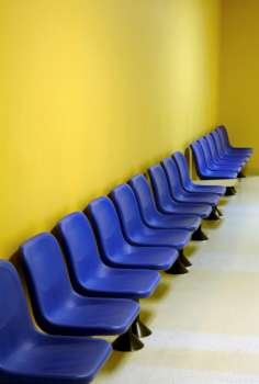 Blue waiting room chairs with yellow wall.