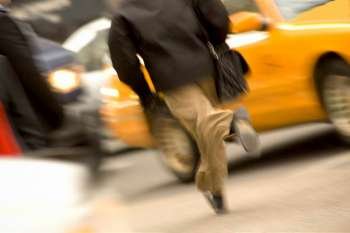 Urban businessman running downtown for taxi in busy city.