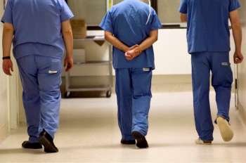 Three physicians walking down hospital hallway.