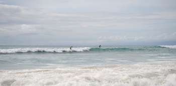 People surfing in ocean along coast of Bali