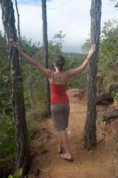 Woman standing between two trees at Mountain Pine Ridge Reserve in Belize