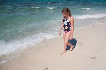 Young girl walking along beach at Belizean Isle in Belize