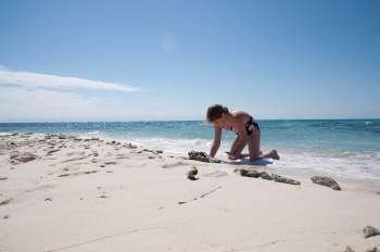 Young girl digging in sand on beach at Belizean Isle in Belize