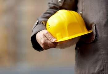 hand of builder with yellow hardhat, natural light,selective focus