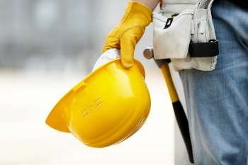 builder with yellow helmet and working gloves on building site