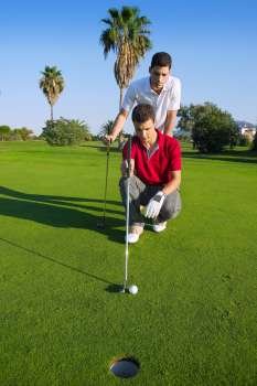 young man playing golf looking and aiming for the hole 
