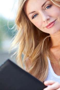 A beautiful young blond woman with stunning blue eyes reading a folder or menu