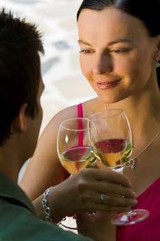 A beautiful young woman and her boyfriend toasting with glasses of white wine while bathed in summer sunshine