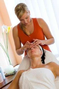 A young woman relaxing at a health spa while having a facial treatment.