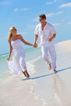 Happy young man and woman couple running, laughing and holding hands on a deserted tropical beach with bright clear blue sky