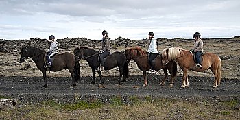 Girls in riding helmets in a row on Icelandic horses
