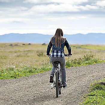 Girl riding bicycle on unpaved country road