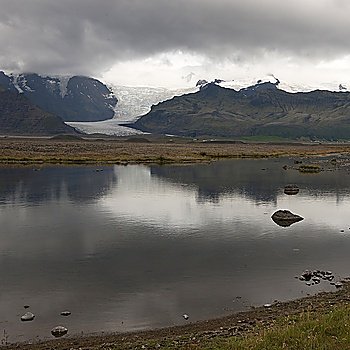 Landscape, glacier through mountain valley, reflected in glacial lake