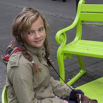 Girl sitting on park bench on sidewalk
