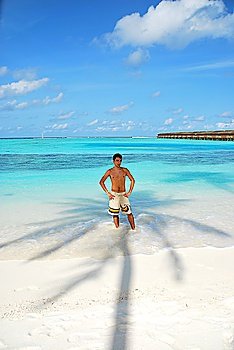 beautiful photo of a young adult standing in the shadow of a palm tree in Maldives