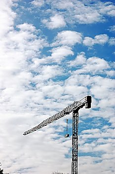 Construction crane parked over a cloudy blue sky