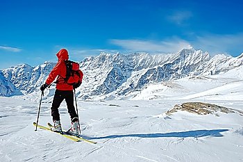 A lonely backcountry skier in a sunny winter day, alpine scenic, horizontal orientation                                    