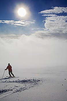 Young male skier on a ski slope; back view