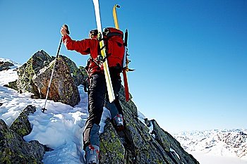 Male ski-climber climbing a rocky ridge; horizontal frame. Italian alps.