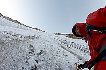 Ice climber on a steep icy route; horizontal frame, copy-space on the left.