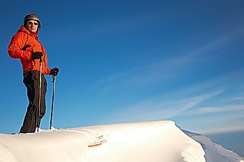 Skier standing at the top of a snowy ridge over a clear blue sky, italian alps; horizontal frame