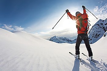 Young skier reaches his arms up over a snowy mountain landscape, italian alps; horizontal frame