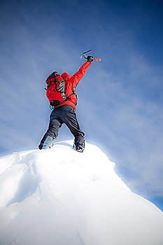Mountaineer reaches the top of a mountain peak and expresses his joy. Vertical frame. Soft-focus version