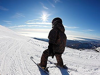 Child skiing on a slope against a clear sky.