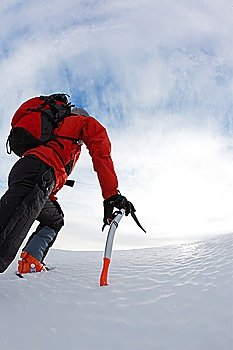 Lone male mountain climber climbing a snowy ridge; vertical frame.
