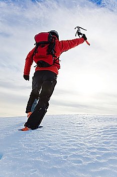 Mountaineer reaching the top of a snowy mountain. Vertical frame.