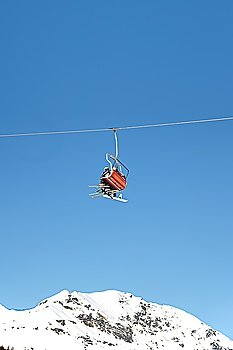 Skiers are riding in chairlift in a ski area, low angle view, Italy. Large copy-space at the top.