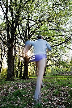 Young man trail running in a forest, blur effect.