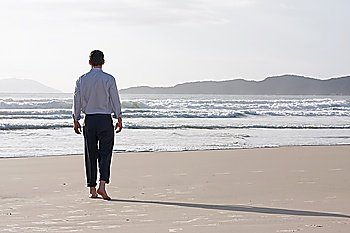 Businessman walking barefoot on a beach