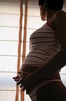 Pregnant woman standing by a window